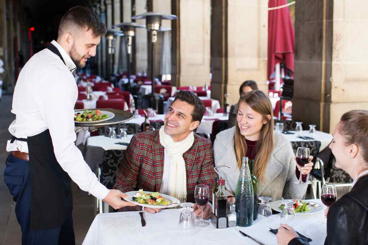 cameriere porta i piatti al tavolo