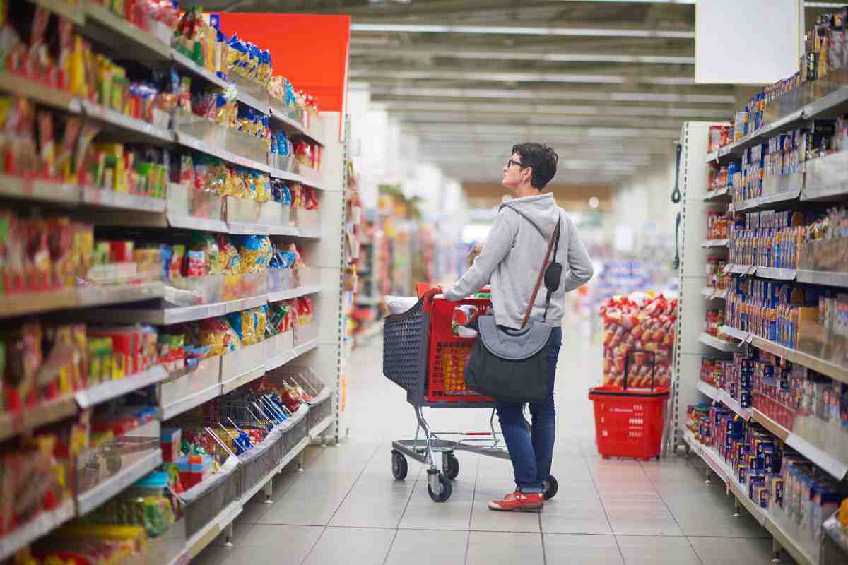 persona che fa la spesa al supermercato tra gli scaffali